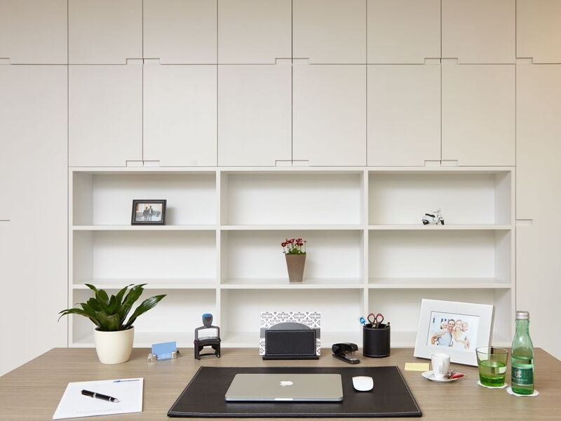 Minimalistischer moderner Schreibtisch mit Laptop, Pflanzen und integrierten weißen Wandregalen