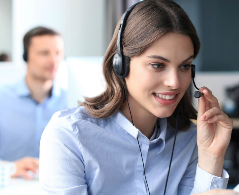 Smiling customer support agent wearing a headset in a call center office