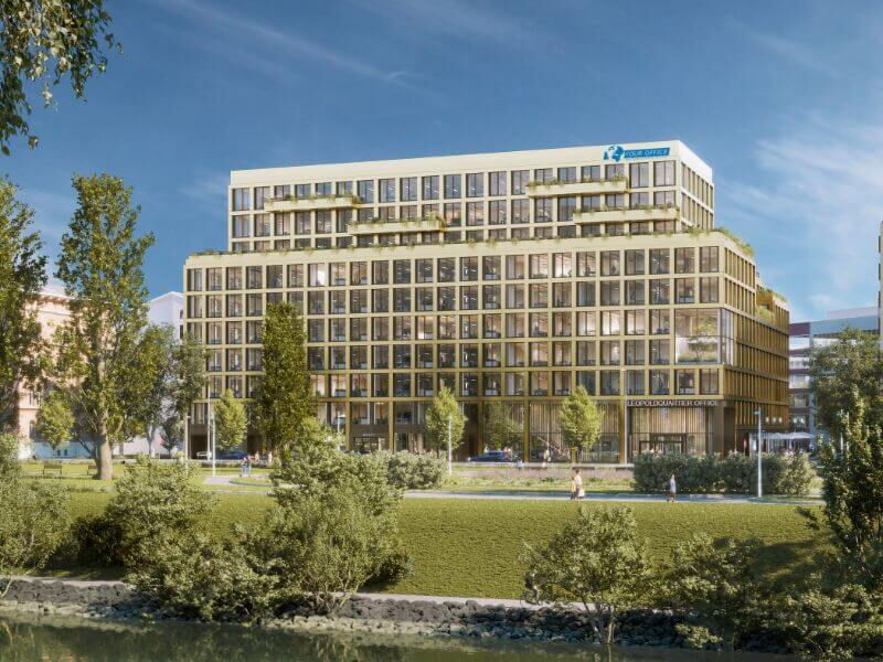 Außenansicht eines modernen mehrstöckigen Bürogebäudes mit großen Fenstern und einer grünen Parkanlage im Vordergrund