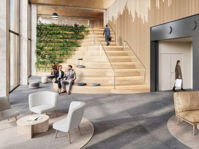 Modern office lobby interior in Leopoldsquartier featuring a large wooden seating staircase, a vertical green wall, and comfortable lounge areas.