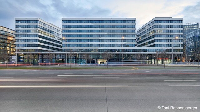 Moderne QBC Bürogebäude Fassade mit Glasfronten und Lichtspuren vom Verkehr in Wien bei Dämmerung, fotografiert von Toni Rappersberger