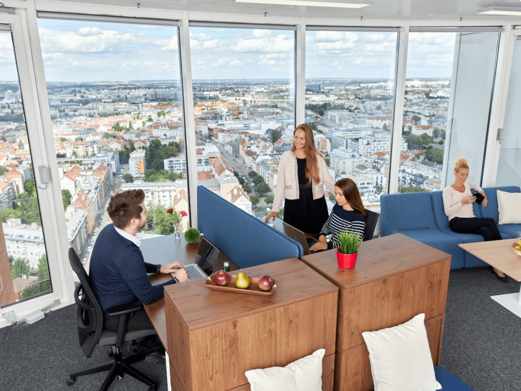 Team von Fachleuten arbeitet in einem hellen, modernen Büro mit großen Panoramafenstern und Blick auf die Skyline