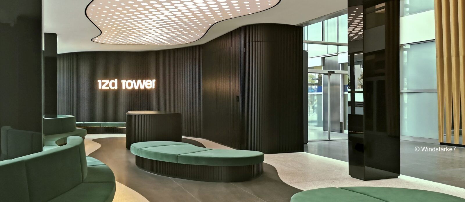 Geräumiges und modernes Foyer des 1zd Towers mit dunklen Rillenwänden, grünen Samtsitzmöbeln und einer einzigartig beleuchteten Decke.