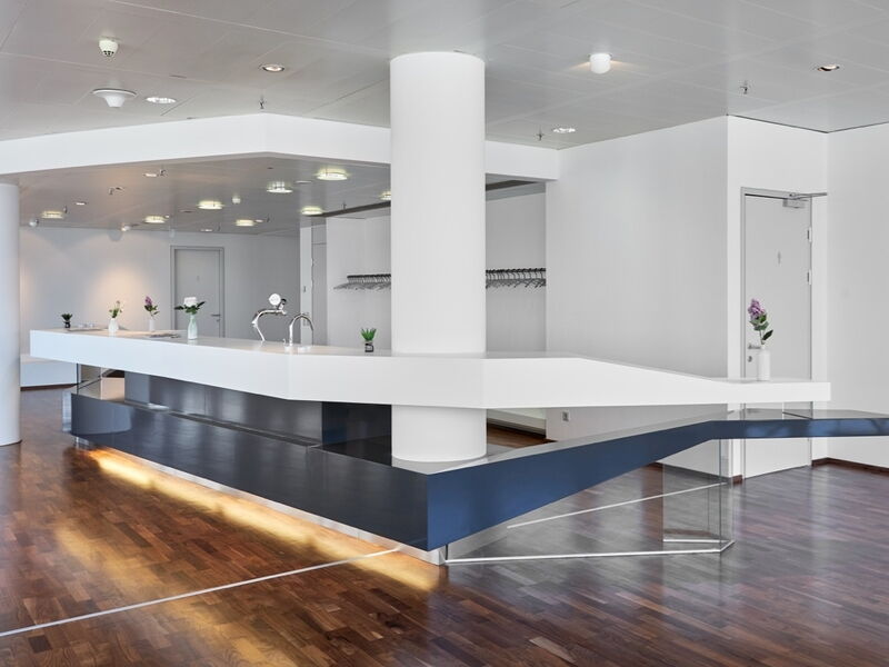 Ein moderner Innenraum mit einer eleganten weiß-blauen Bar, Holzboden und minimalistischer Architektur.