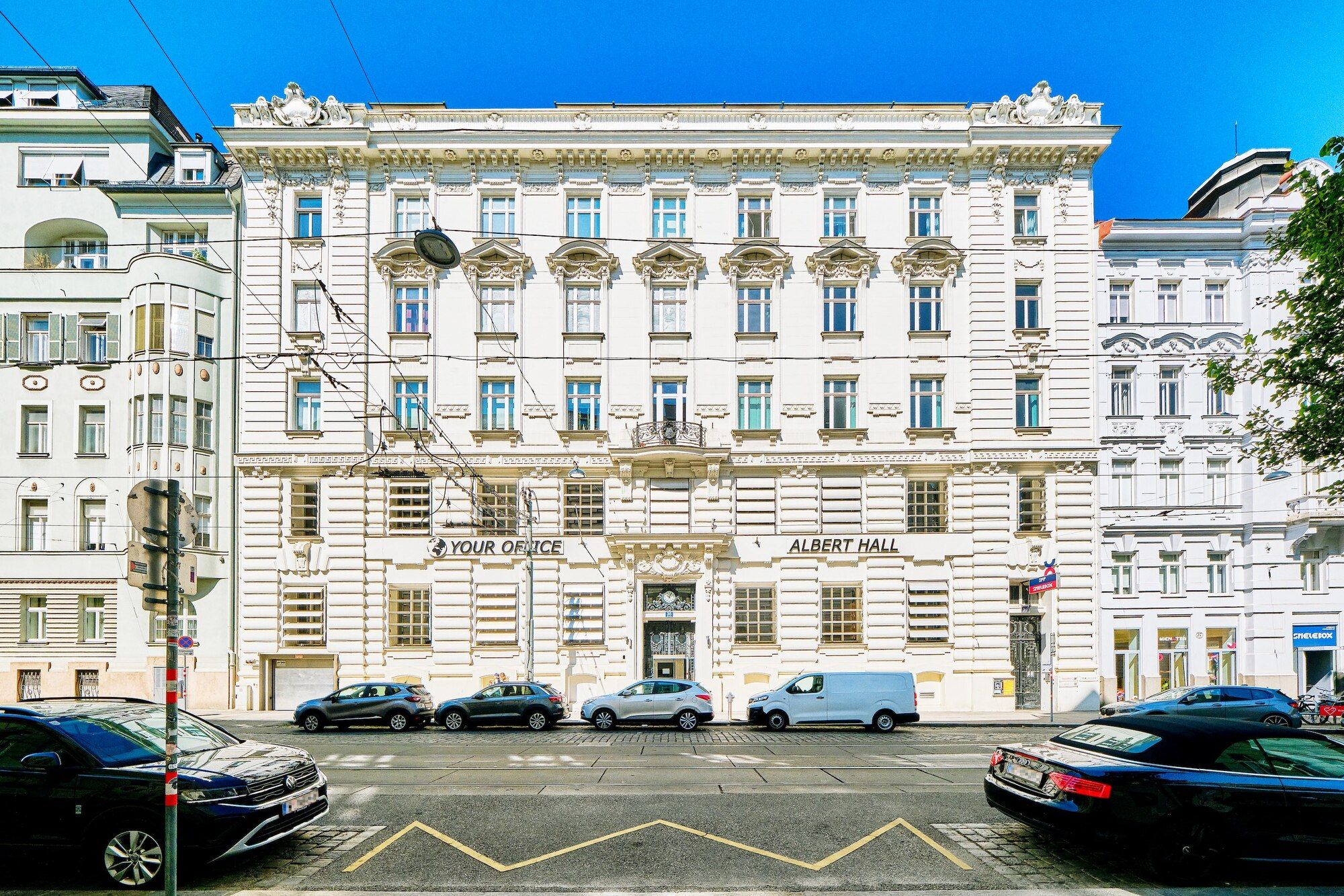Klassische weiße Fassade des Albert Hall mit parkenden Autos entlang der Straße unter klarem blauem Himmel