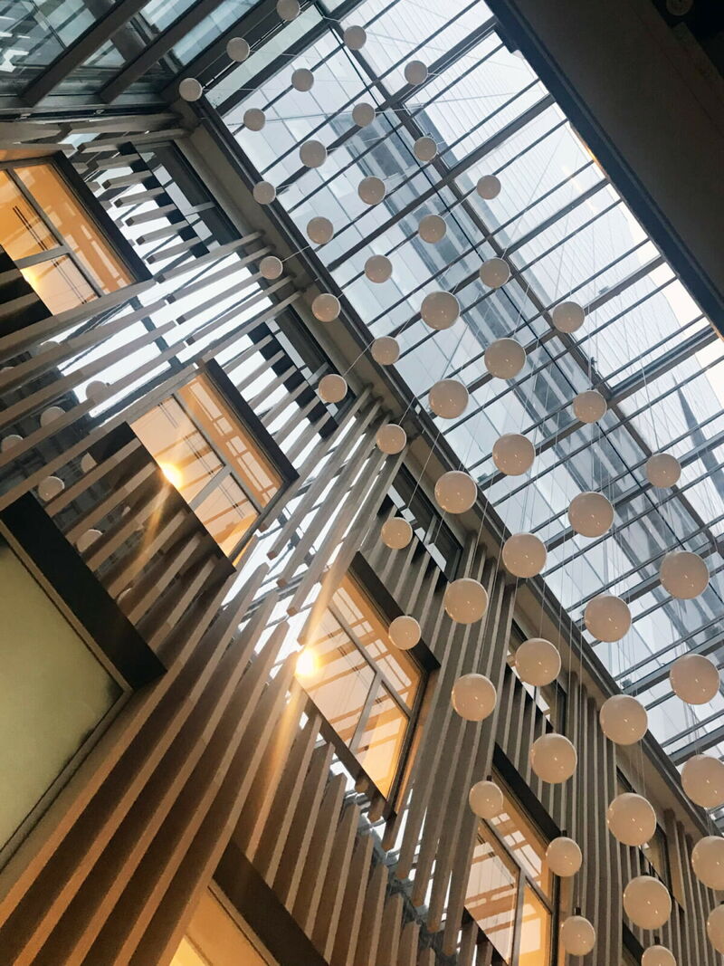 Interior view of a modern gallery with a glass atrium roof and decorative hanging white spheres