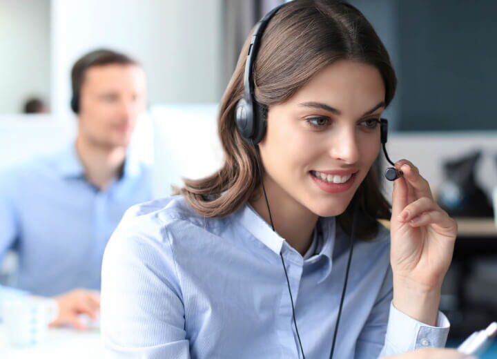 Freundliche Mitarbeiterin im Kundenservice mit Headset in einem Callcenter Büro
