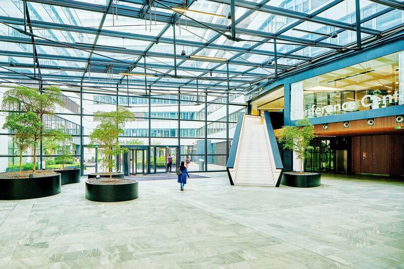 Geräumiges, modernes Atrium im EuroPlaza mit Glaskuppel, Innengestaltung mit Bäumen, Treppe und Konferenzcenter-Eingang
