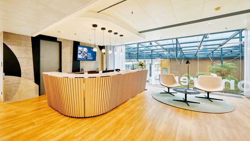 Geräumiger und moderner Büro-Empfangsbereich im EuroPlaza mit großer Holz-Rezeption und gemütlicher Lounge-Bestuhlung.