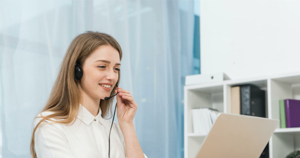 Smiling female customer support representative wearing a headset in an office