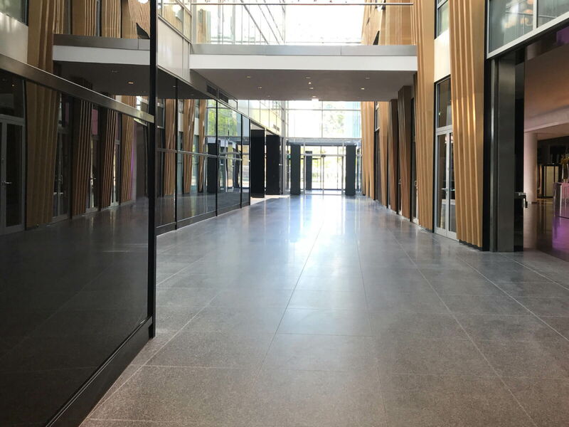 Spacious modern office building interior featuring a long polished hallway, wooden architectural accents, and glass facades