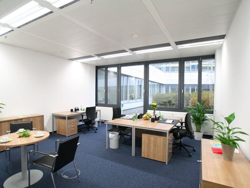 Moderne Büroinneneinrichtung mit Holztischen, ergonomischen Stühlen und großen Fenstern im Euro Plaza
