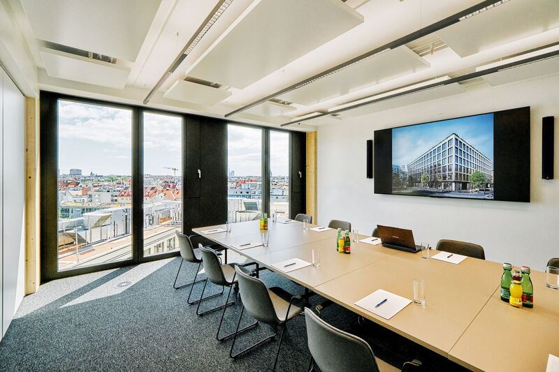 Bright and modern conference room with a large meeting table, presentation screen, and panoramic city view through large windows.